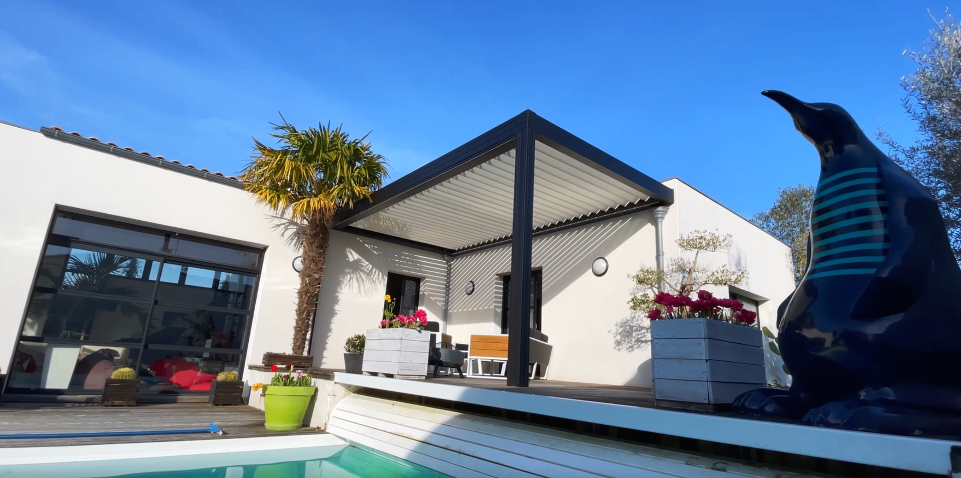 Pergola bioclimatique anthracite à lames orientables installée au bord d'une piscine